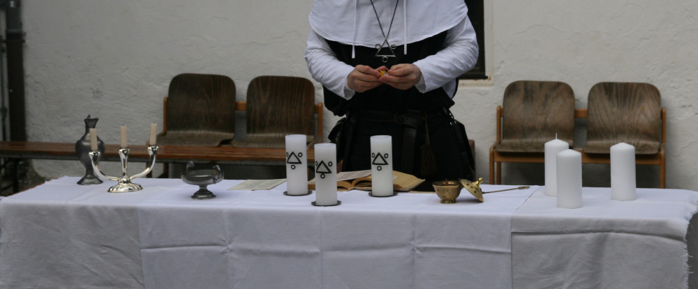 Ein Schrein des Gottes Zei. Es stehen drei Kerzen und eine Schale darauf.